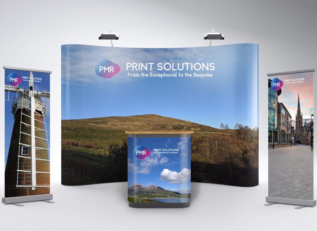 Exhibition display stands including roller banners, pop‑up displays and fabric stands arranged in a trade show setting.
